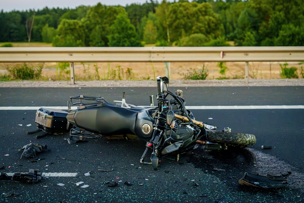 A motorcycle lying on a highway with debris after a collision, emphasizing the dangers of drivers failing to yield to riders.