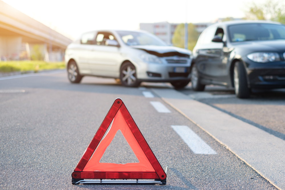Scene of a low-speed car accident with a warning triangle placed on the road, representing a typical fender bender situation.